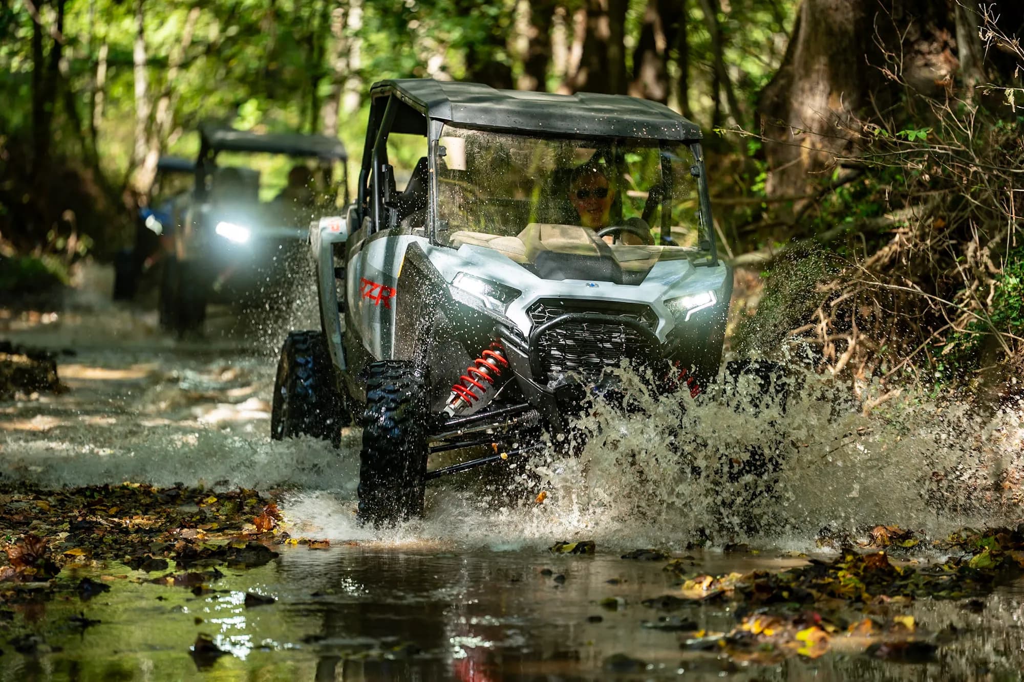 A guest driving a side by side through a creek crossing